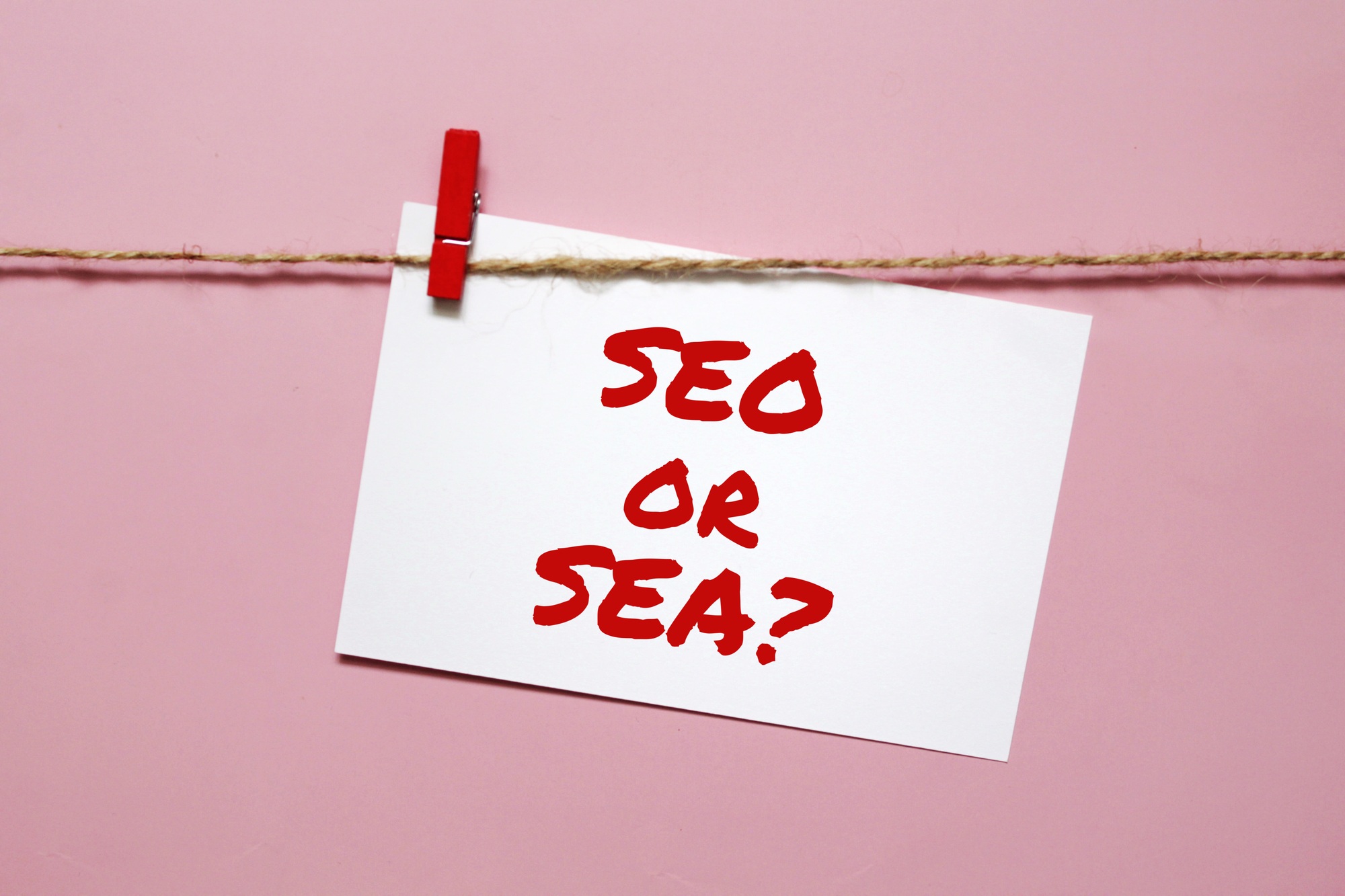 Sticker with the inscription seo or sea hanging on a rope on a pink background Sticker with the inscription seo or sea hanging on a rope on a pink background
